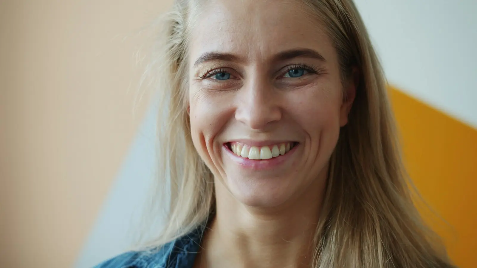 Glimlachende vrouw met blond haar in een spijkerjasje